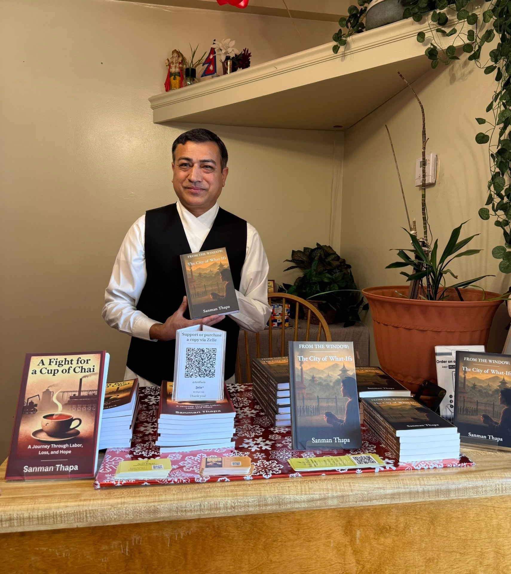 Sanman Thapa holding From the Window: The City of What Ifs at his signing table
